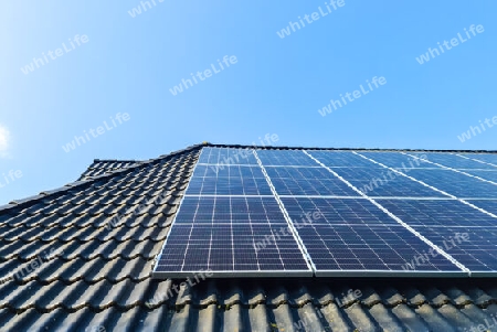 Solar panels producing clean energy on a roof of a residential house with black roof tiles