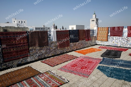 Eine Dachterrasse mit Teppichen und die Moschee Zaytouna oder Grosse Moschee im Souq oder Bazzar in der Altstadt  von Tunis am Mittelmeer in Tunesien in Nordafrika..