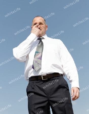 a thoughtful businessman outdoors with blue background