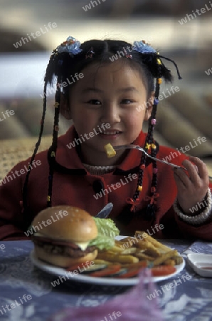a girl with a hanburger in a restaurant in the town of Yangshou near the city of  Guilin in the Province of Guangxi in china in east asia. 