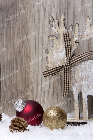 Weihnachten, Dekoration mit Holzhintergrund, Schnee, Elch, Weihnachtskugeln gold und rot und Tannenzapfen 