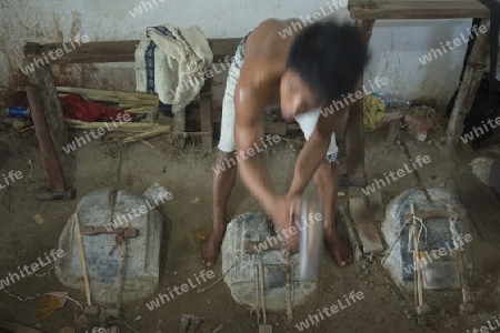 workers pound sheets of Gold leaf at a Gold pounder Factory the City of Mandalay in Myanmar in Southeastasia.