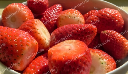 Fresh strawberries are poured into a white bowl