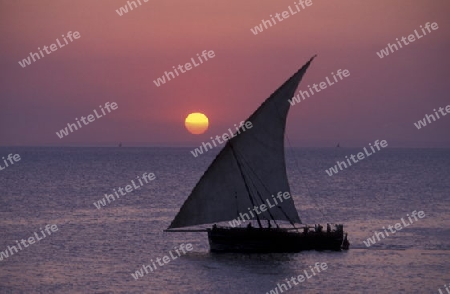 Ein Segelboot bei Sonnenuntergang vor der Altstadt in Stone Town der Hauptstadt der Insel Zanzibar oestlich von Tansania im Indischen Ozean.
