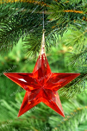 Dekorativer Weihnachtsschmuck an einem Tannenzweig auf gruenem Hintergrund