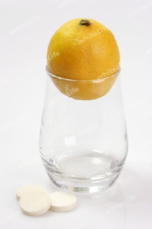 Zitrone mit einem Glas und Brausetabletten auf hellem Hintergrund