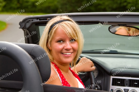 Junge blonde Frau am Steuer eines Cabriolets