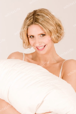 blonde Haaren stehend mit Kissen Kissen. Sie traegt ein Nachthemd und laechelt / blonde hair, standing with pillow cushions. She is wearing a nightgown and smiles