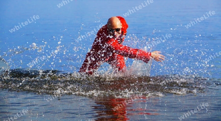 Bald man with sunglasses and red suit splashing the blue water - Mann mit Glatze, Sonnenbrille und rotem Overall plantscht im blauen Wasser