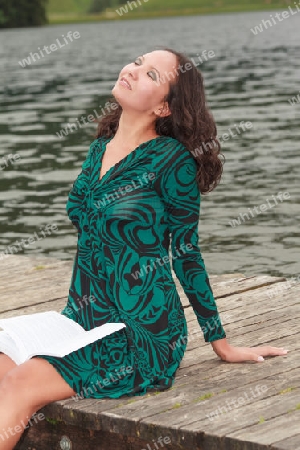 Attraktive Frau entspannt sich beim lesen am See
