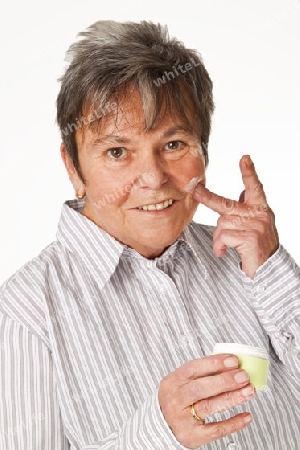 Seniorin mit Cremetopf freigestellt auf weissem Hintergrund