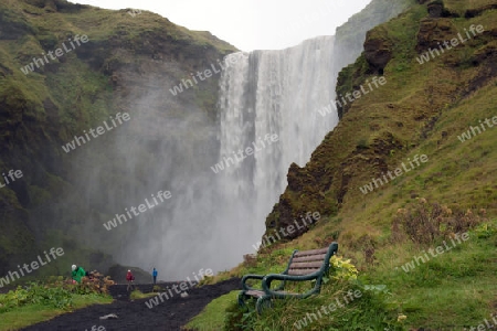 Der S?den Islands, Sitzbank am  malerischen Wasserfall Skogafoss, der hier in einer Breite von 25 Metern bis zu 60 Meter tief ?ber die Flu?kante des Sk?g? herabst?rzt, zum Ausruhen und geniessen