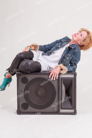 Reife Frau posiert auf einem Lautsprecher