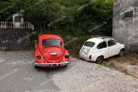Zwei alete Autos an der Bergstrasse und Landschaft ueber dem Ufer des Skadar See oder Skadarsko Jezero bei Godinjei in Montenegro in Europa.    
