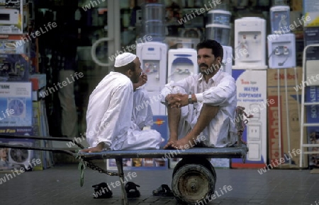two transport worker in the souq or Market in the old town in the city of Dubai in the Arab Emirates in the Gulf of Arabia.