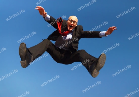 Man in suit with glasses jumping under a blue sky - Mann in Anzug mit Brille und Glatze unter blauem Himmel                               