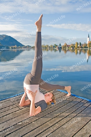 Junge Frau beim Yoga am See
Young woman doing yoga by the lake