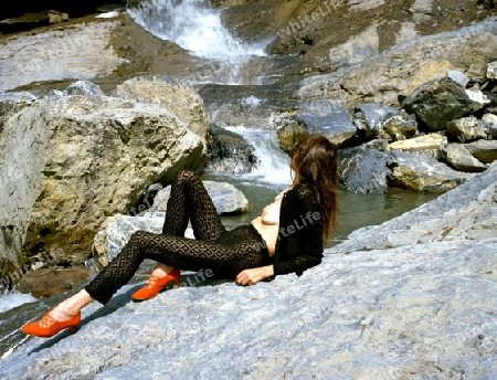 Frau sonnt sich oben ohne vor Wasserfall