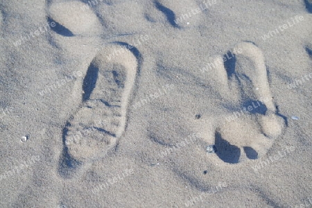 Fußabdrücke barfuß und mit Sohle im Sand